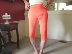 Male slut in skin-tight, bright orange spandex leggings.